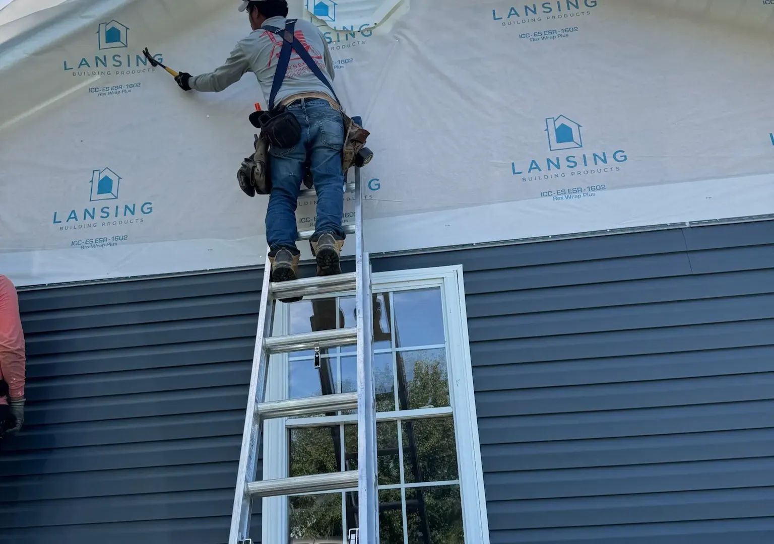 Global Restoration crew member installing new siding on a Kentucky home